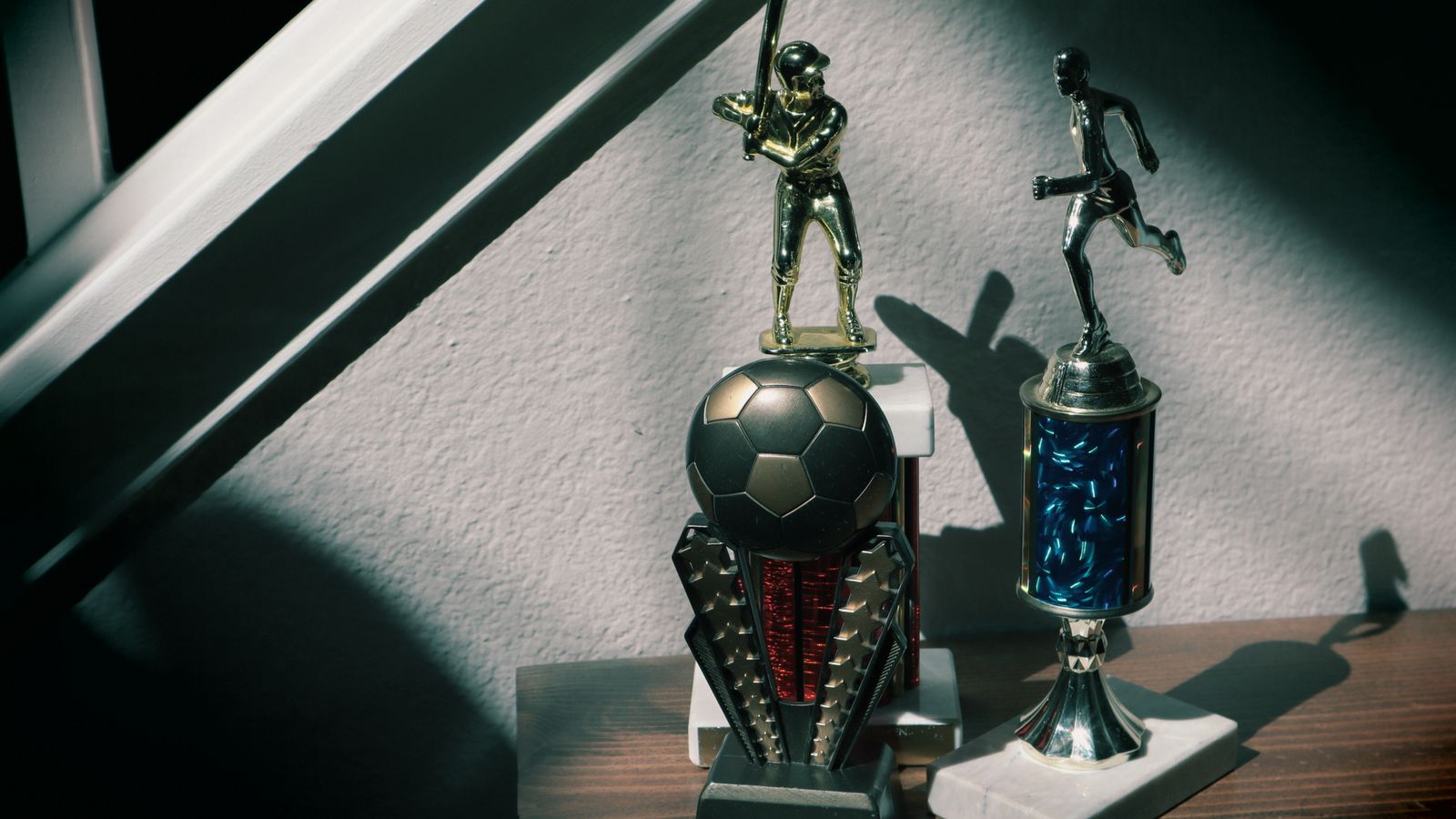 A collection of soccer and baseball trophies displayed indoors, capturing childhood nostalgia.