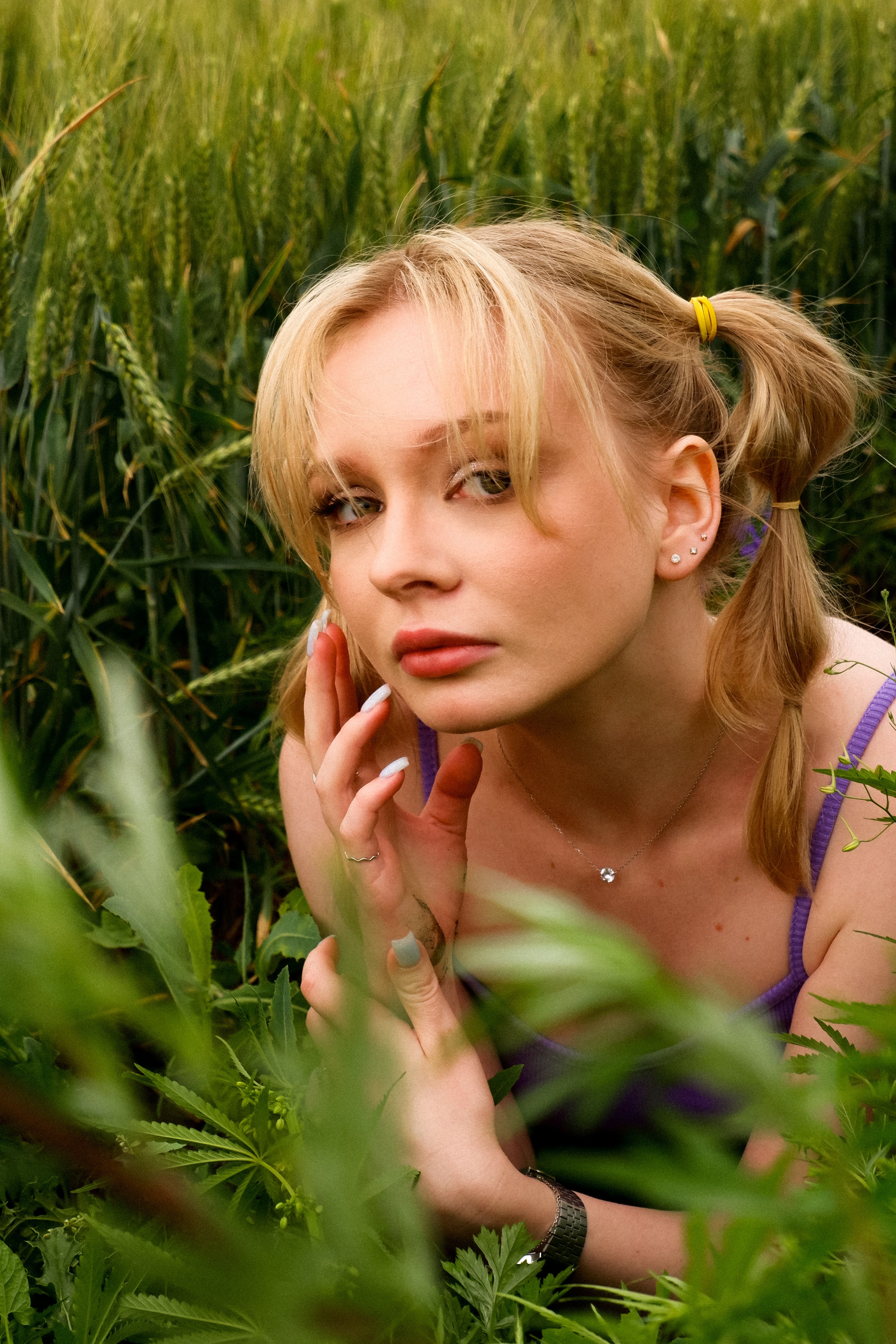 Blonde woman with ponytails in a green field, spring setting.