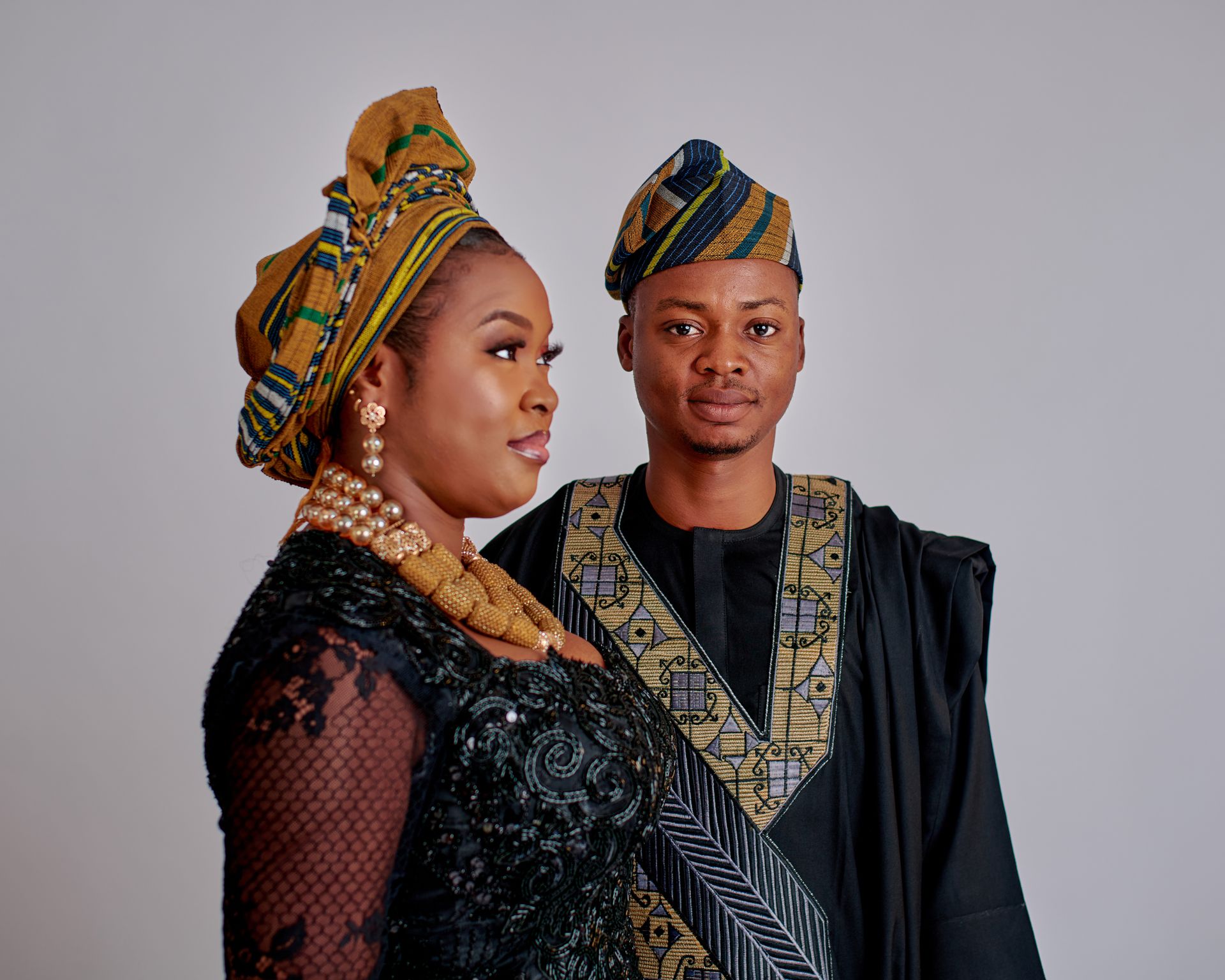 A stylish couple in traditional African garments posing confidently indoors.