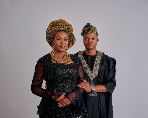 Free Couple wearing traditional African attire with vibrant headwear on neutral background. Stock Photo