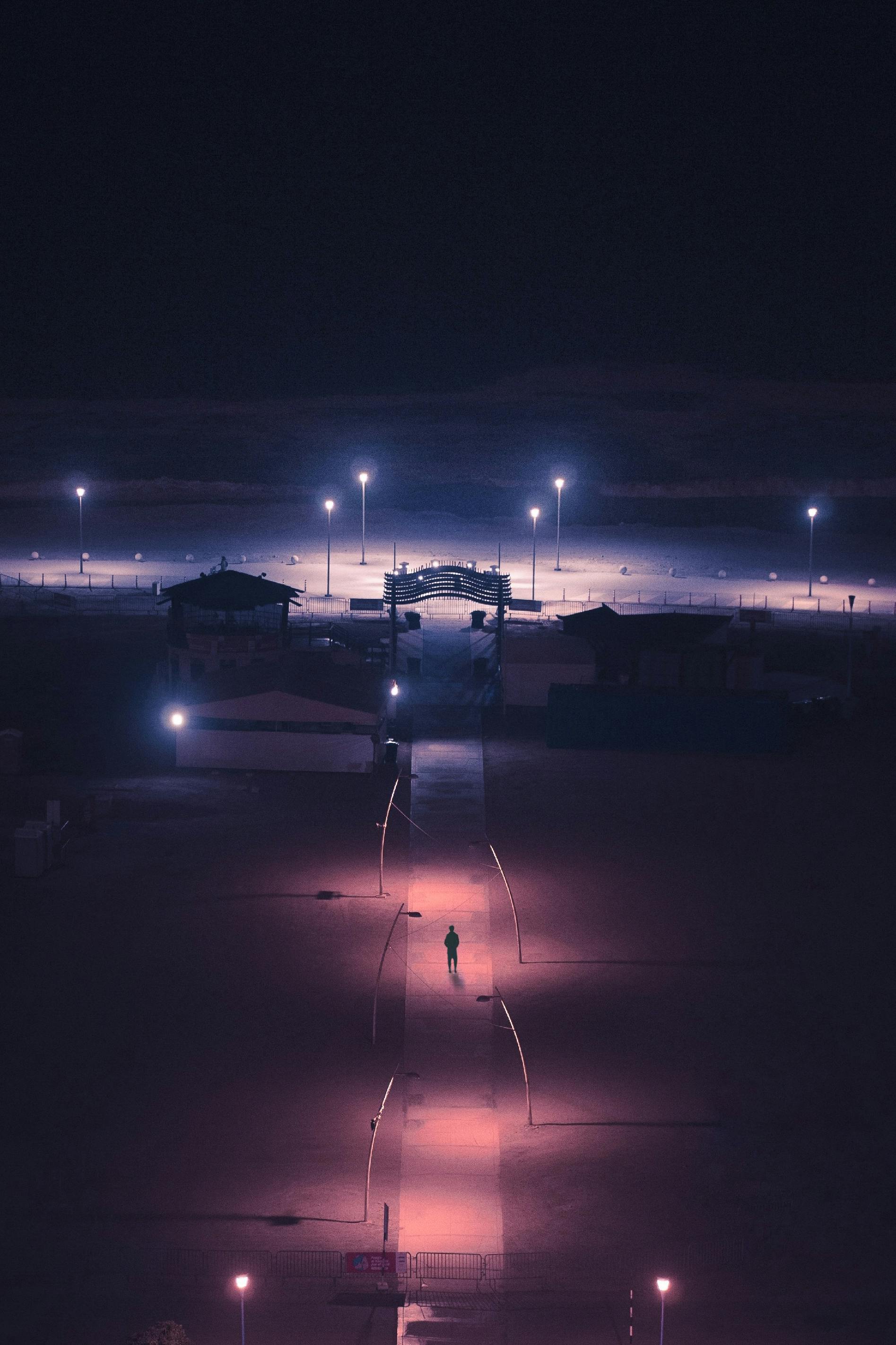 grátis Cena noturna sombria em um calçadão iluminado na praia de Lima, Peru, com um caminhante solitário. Foto profissional
