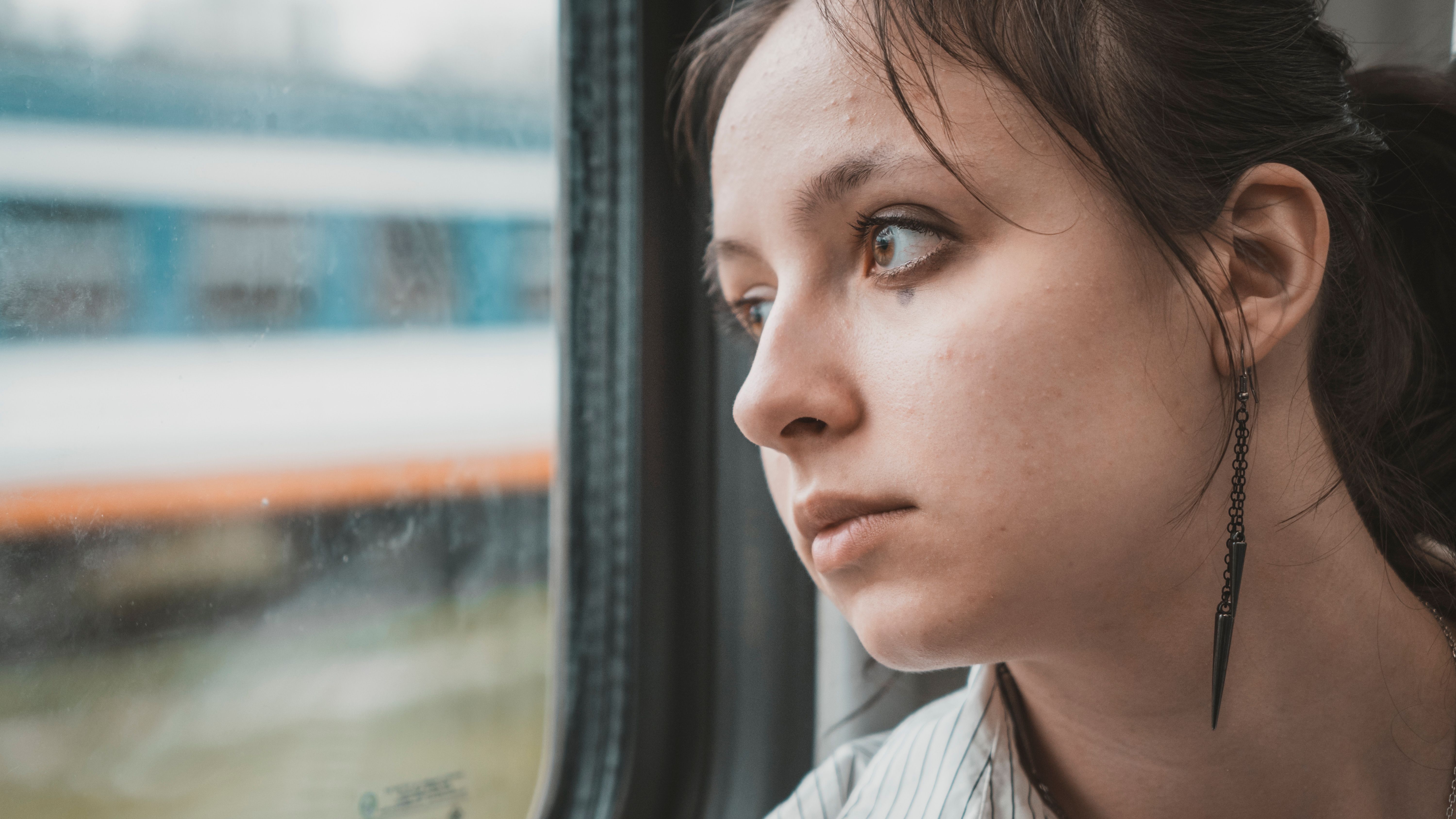 Young woman reflecting while looking out of a train window during travel.