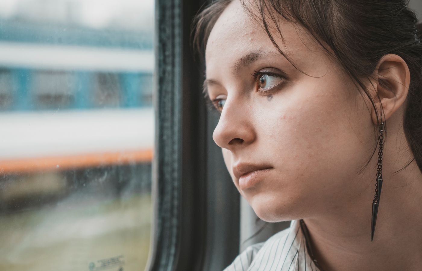 Young woman reflecting while looking out of a train window during travel.