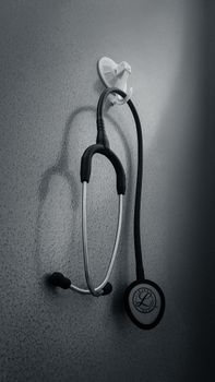 Monochrome image of a stethoscope hanging on a wall, conveying a medical theme.