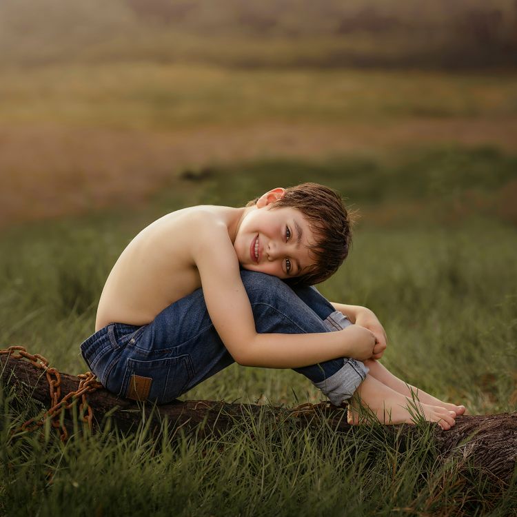 Happy Child Sitting on Log in Sunny Field · Free Stock Photo