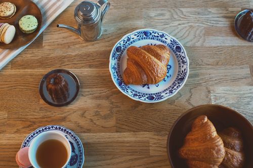 Free Delightful breakfast spread with croissants, tea, and pastries on a wooden table. Stock Photo
