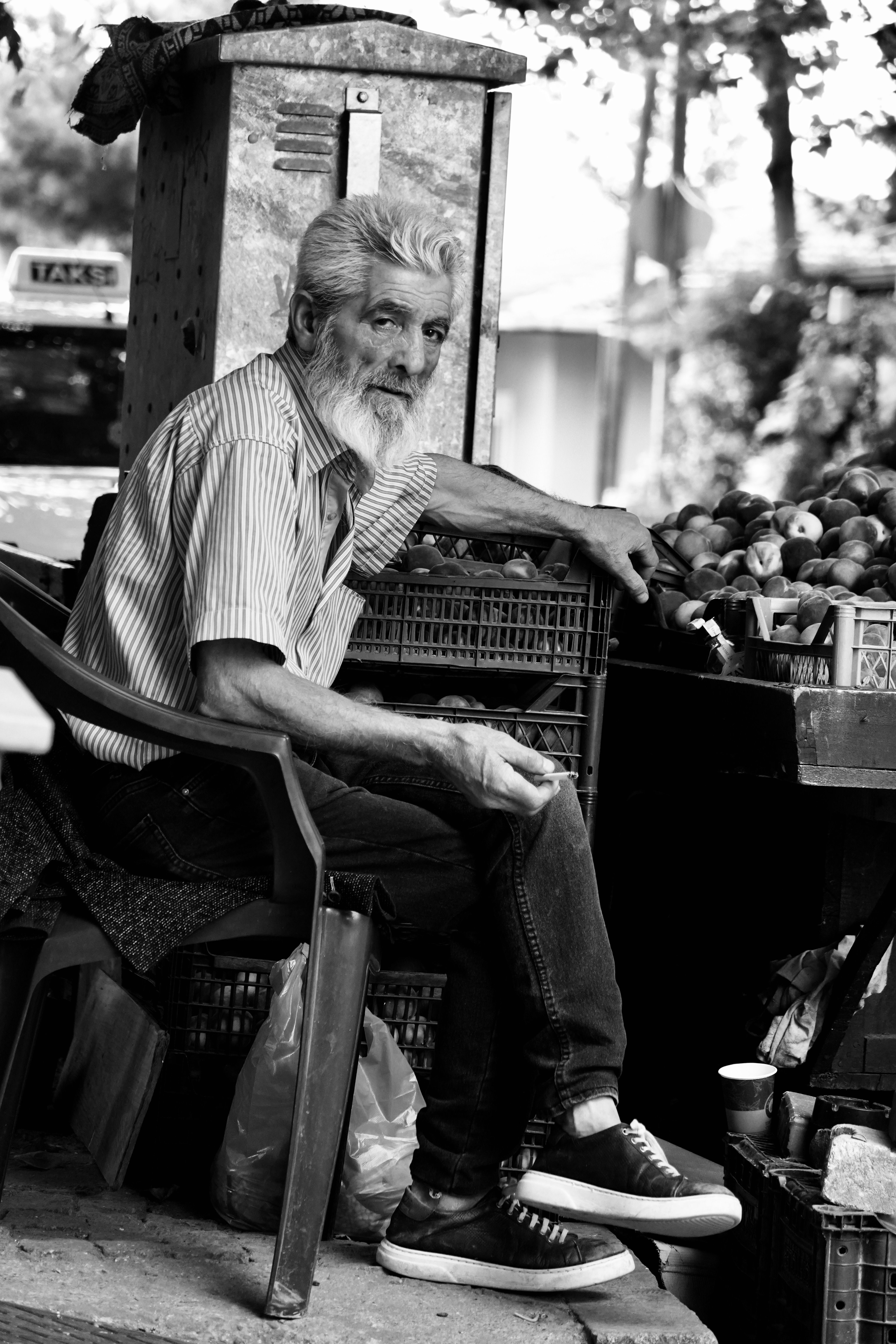 Gratuit Photo en noir et blanc d'un homme âgé assis près d'un étal de marché avec des fruits. Photos