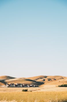 Scenic rural landscape with rolling hills under a clear blue sky, ideal for peaceful getaways.