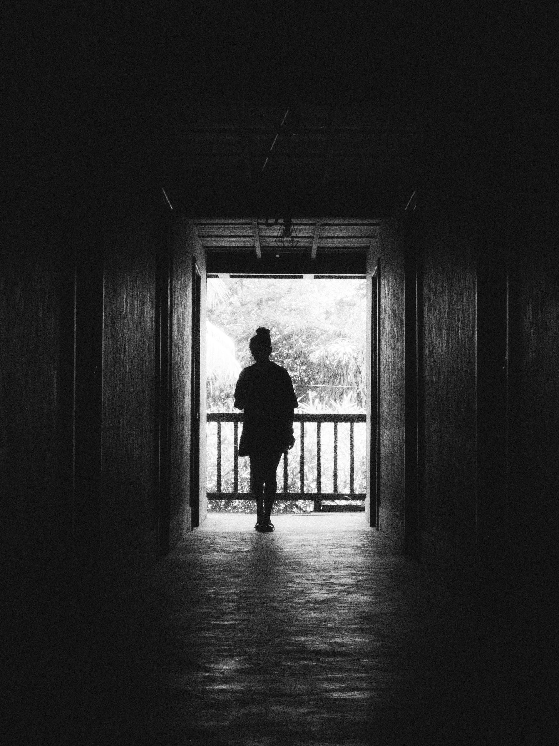 Figura en un umbral entre sombra y luz, representación de introspección y sentido interior