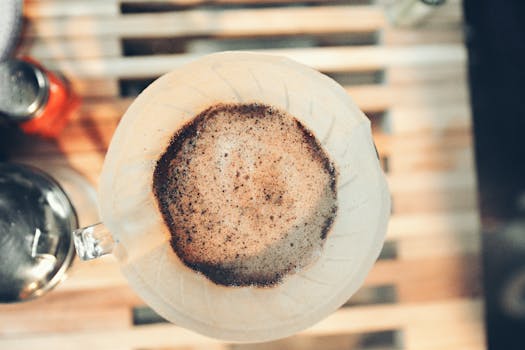 Aerial shot of a coffee dripper brewing fresh coffee on a wooden table.