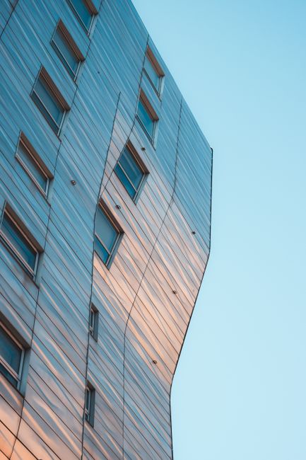 A modern skyscraper in New York City reflecting sunset colors with a unique design and smooth facade.