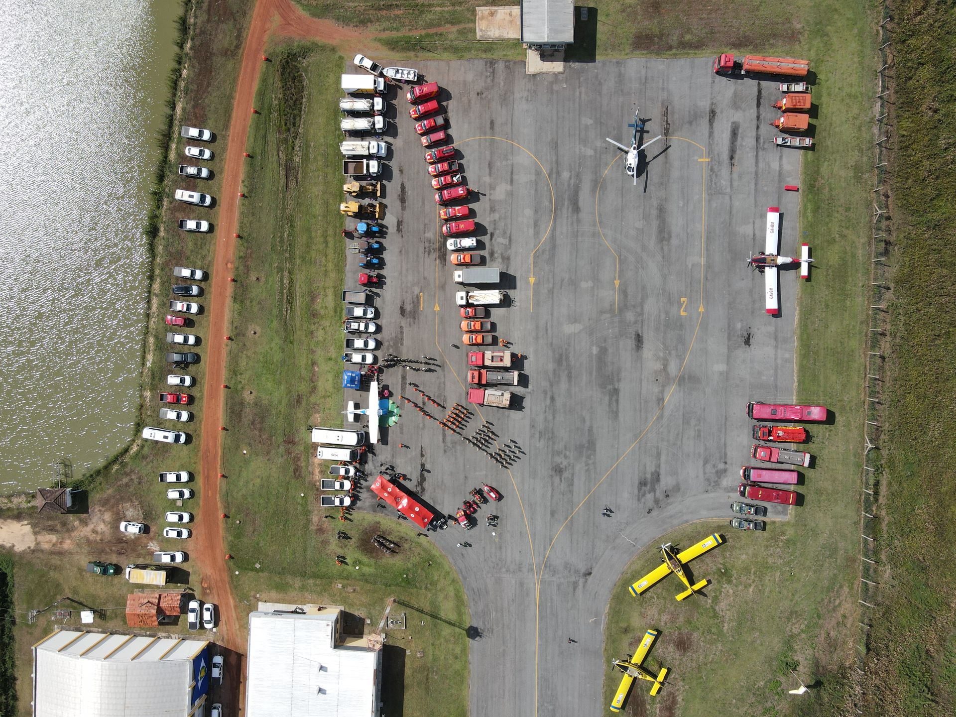 Aerial view of assembled firefighting vehicles and equipment at an outdoor event, showcasing organized emergency response preparation.