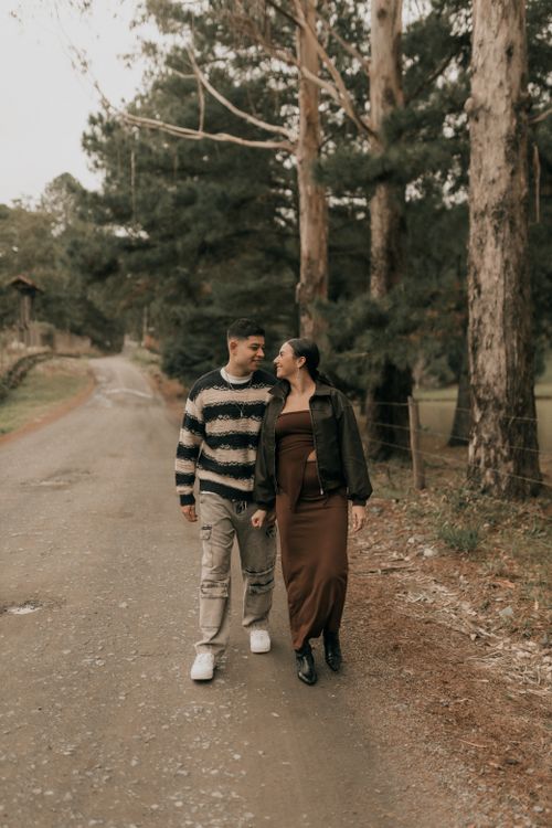 Free Young couple walking together on a forest path, embracing nature's tranquility in cozy outfits. Stock Photo