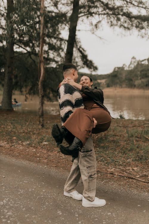 Free A loving couple shares a joyful moment by the lake, surrounded by nature. Stock Photo