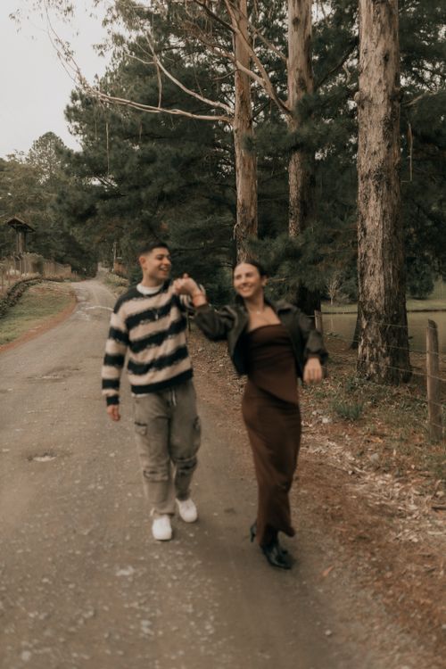 Free Smiling couple walking hand-in-hand down a forest path, enjoying a pleasant day outdoors. Stock Photo