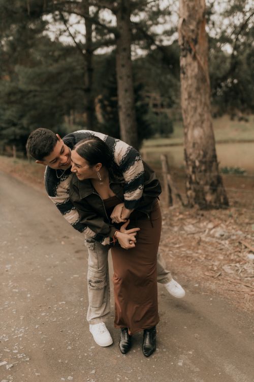 Free A couple shares a joyful moment on a serene forest path during autumn. Stock Photo