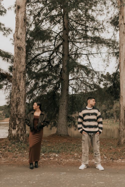 Free Stylish couple standing apart in an autumnal forest setting with tall trees. Stock Photo