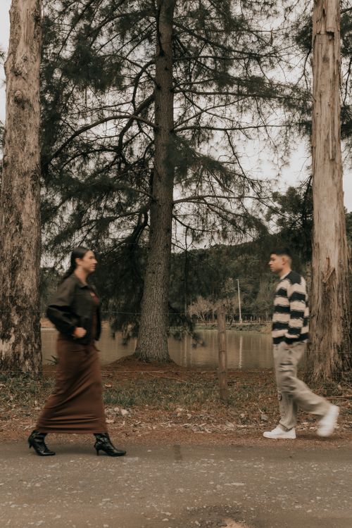 Free Two young adults walking along a forest path in autumn, with trees lining the background. Stock Photo