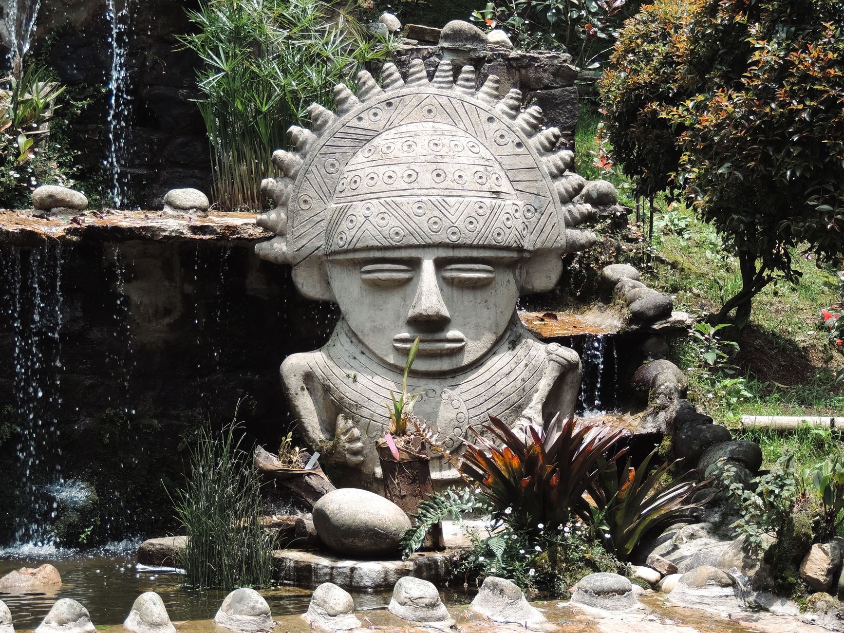 Stone sculpture inspired by Pre-Columbian design in a lush Bogotá garden setting.