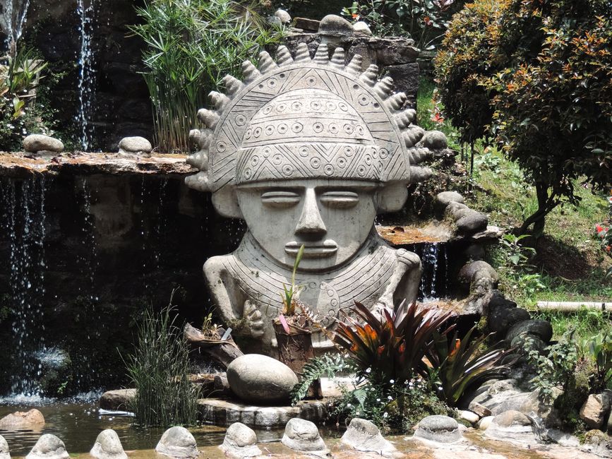 Stone sculpture inspired by Pre-Columbian design in a lush Bogotá garden setting.