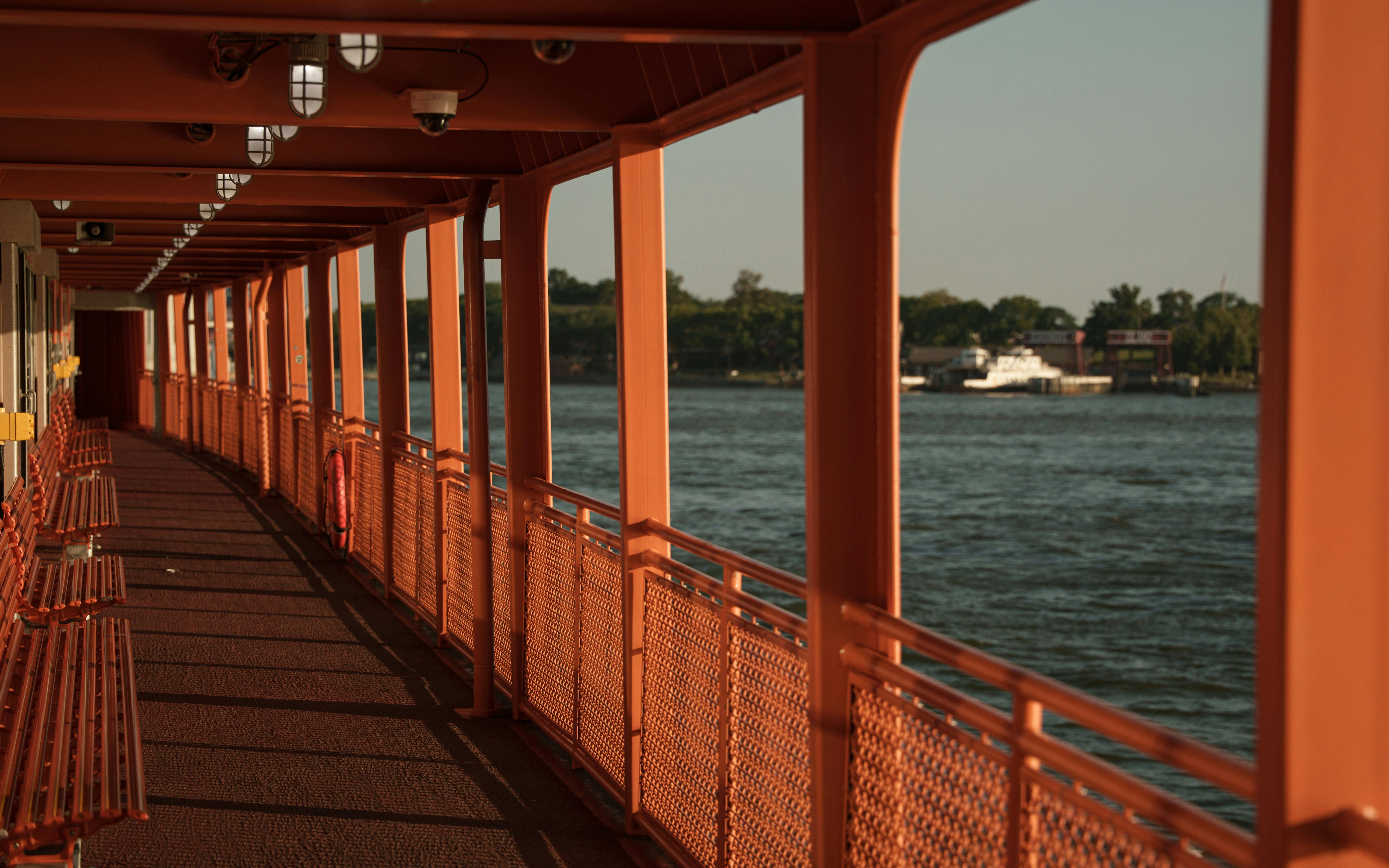 Empty Staten Island Ferry deck with scenic water view during sunset in New York City.