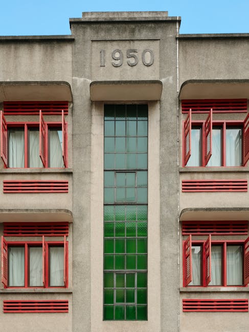 Close-up of a 1950 building facade featuring red windows and green glass panels.