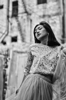 一位时尚女性在户外摆出梦幻般的表情，构成一幅优雅的黑白肖像