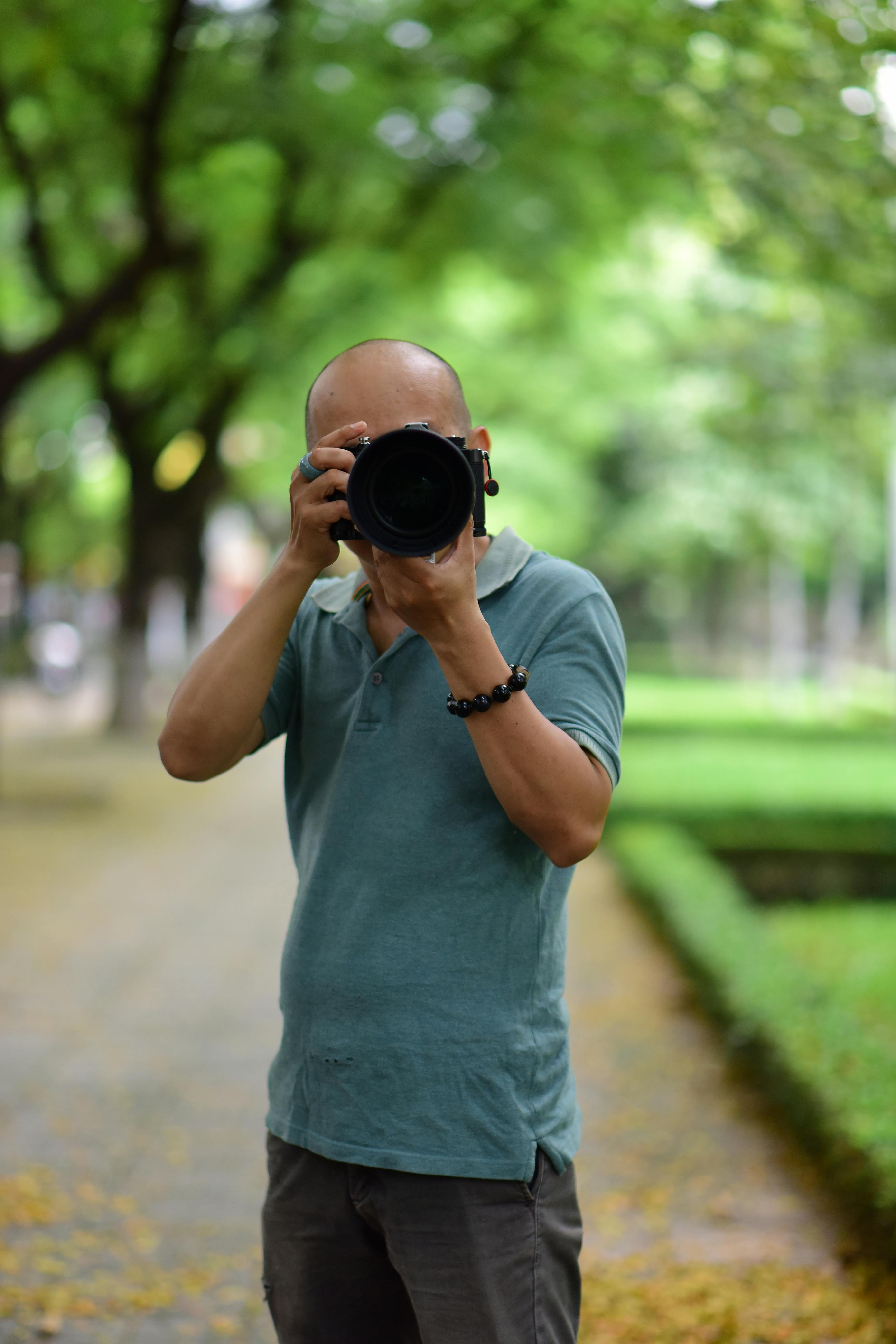 Photographer taking pictures in a lush green park, showcasing creativity and nature.