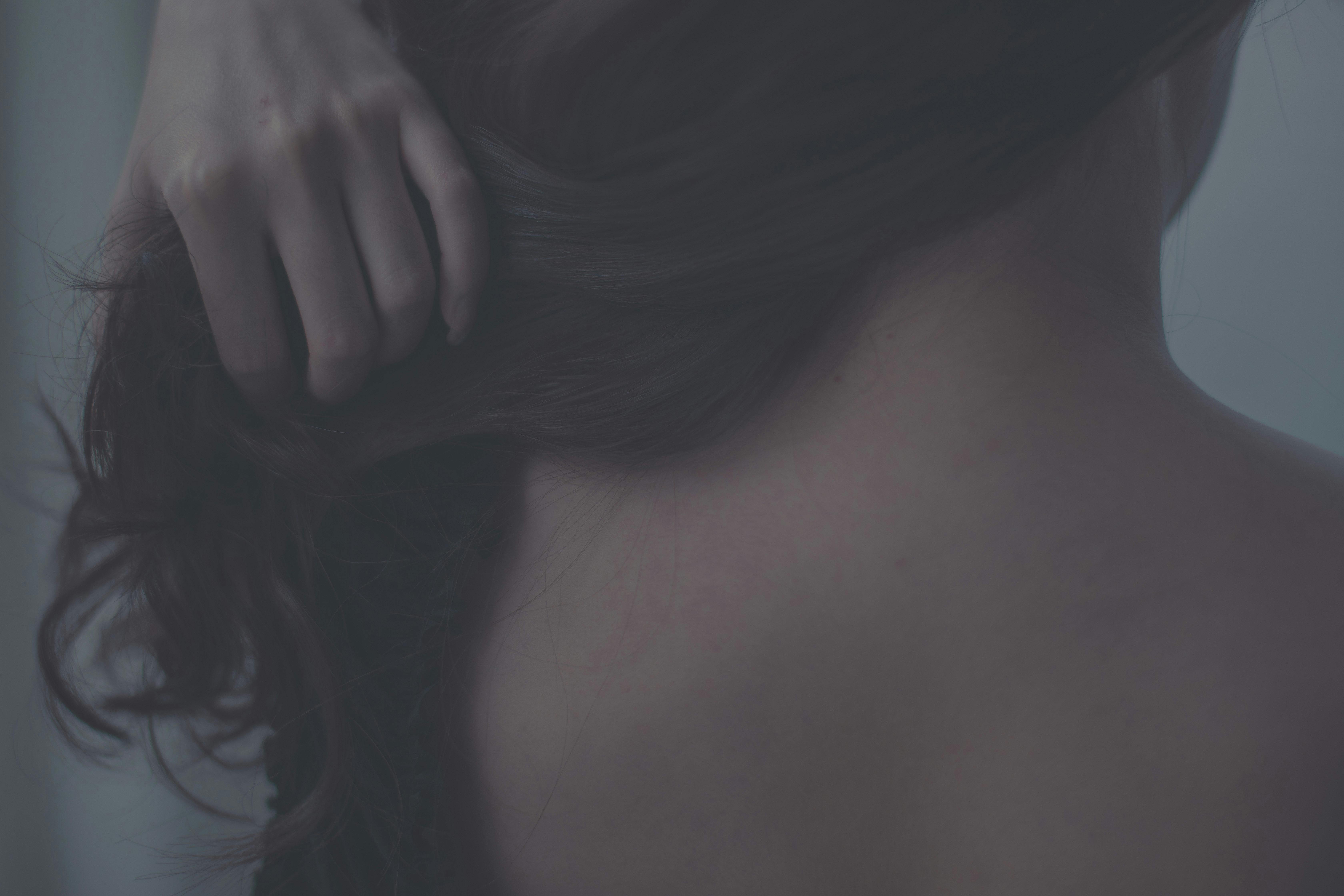 Artistic close-up of a woman gently touching her hair, capturing soft textures and intimate mood.