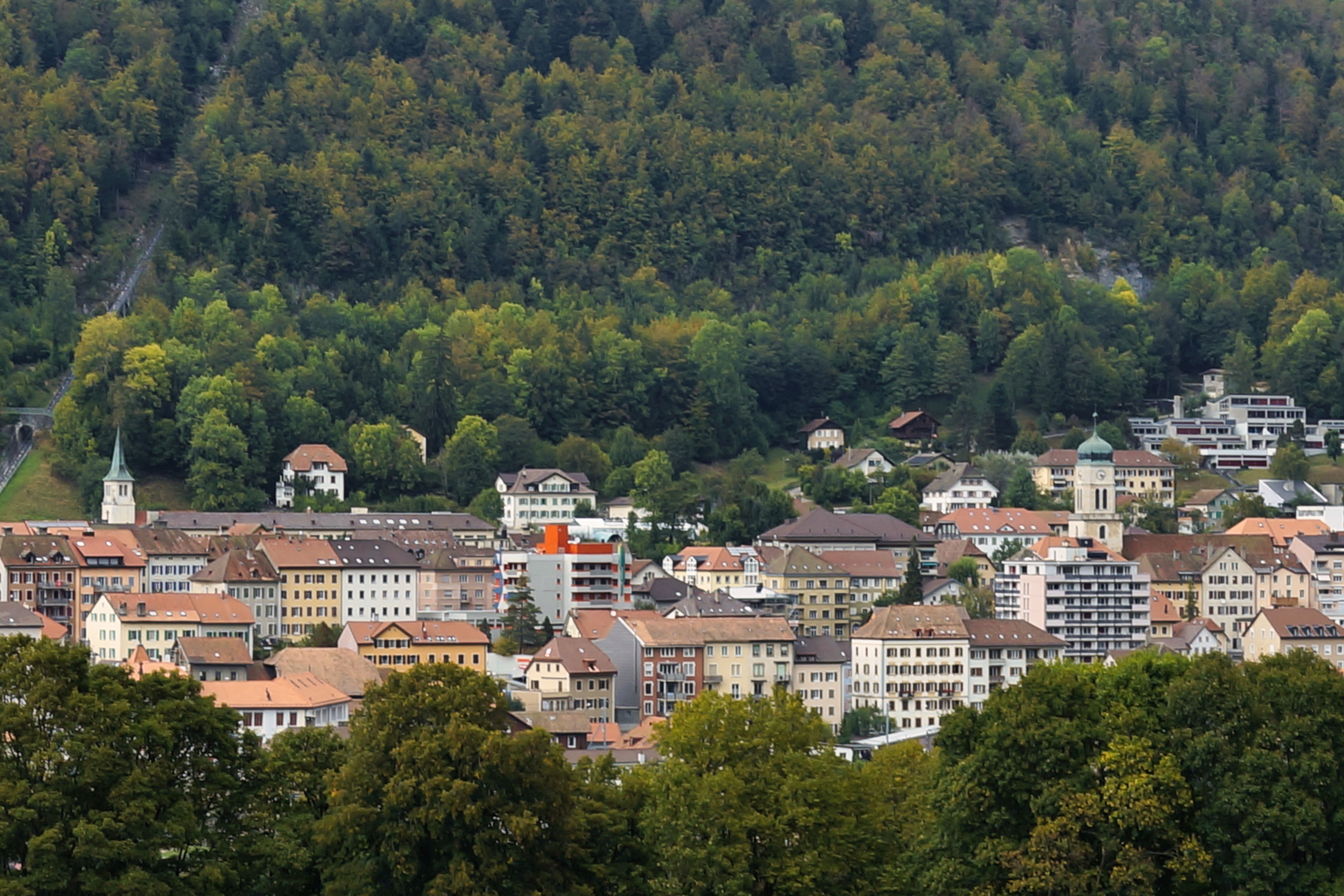 Charming town of Saint-Imier nestled against a lush forested hillside.
