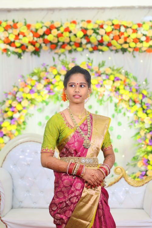 Free Beautiful Indian woman in a traditional saree with floral jewelry, posing indoors. Stock Photo