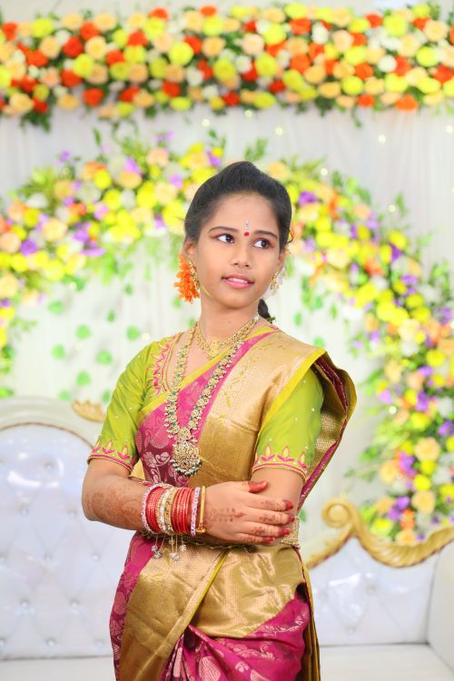 Free A woman in colorful traditional Indian sari with floral jewelry and henna, posing indoors. Stock Photo