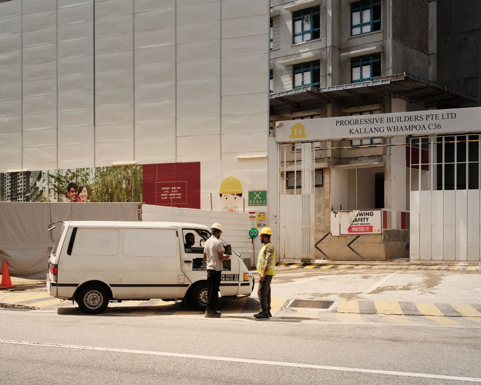 Construction workers interacting near a van at a building site in Singapore.