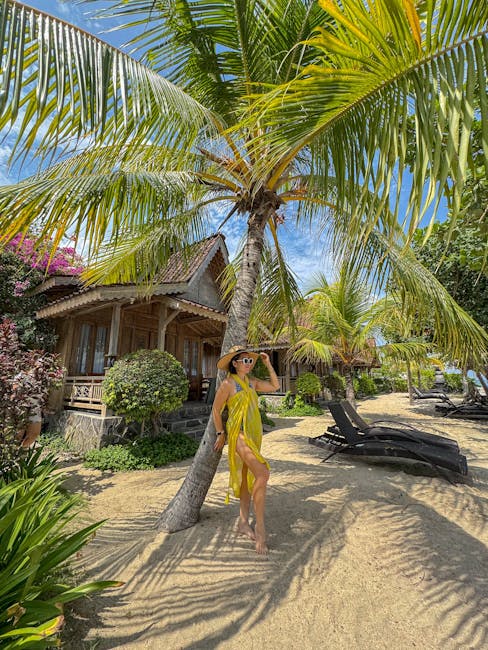 Woman in yellow dress enjoying a sunny day at a tropical beach resort in Bali under palm trees.