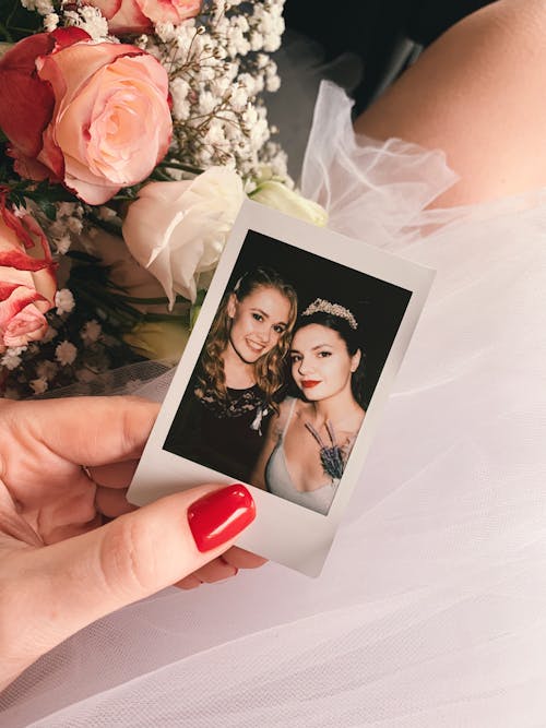 Unrecognizable Woman Hand Holding Photo of Bride and Her Friend