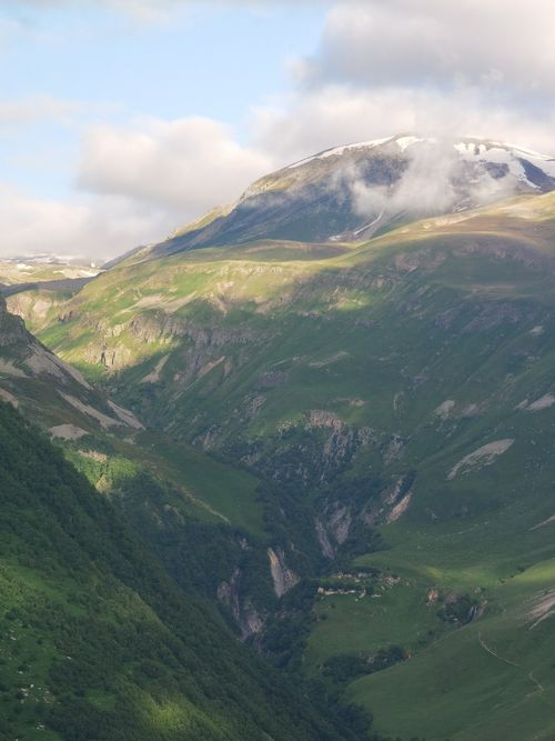 Free Breathtaking view of green valleys and snow-capped mountains in Kazbegi National Park, Georgia. Stock Photo