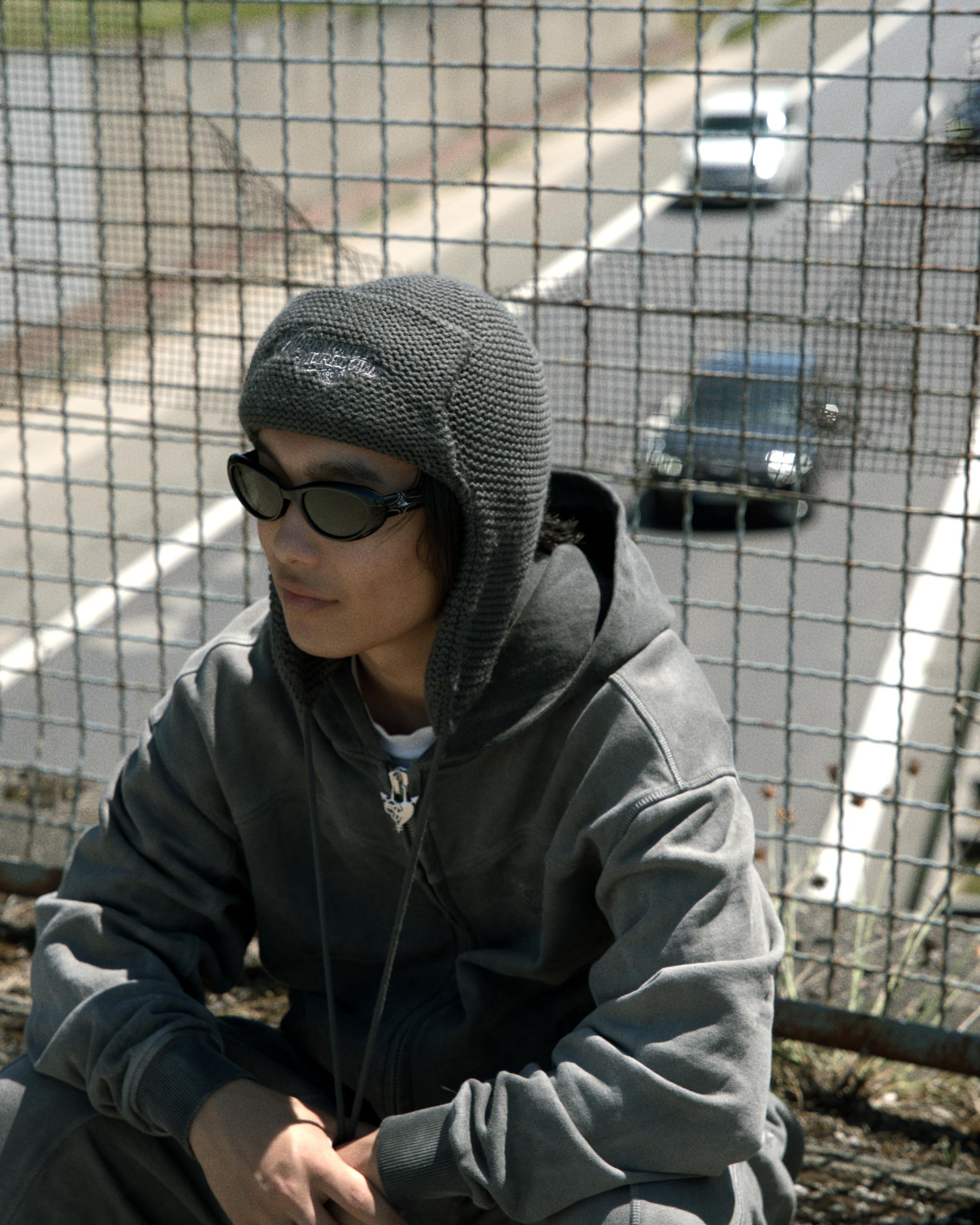 Kostnadsfria En trendig person i solglasögon sitter vid en motorväg och utstrålar en cool urban atmosfär. Stock foto