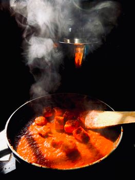 Steaming hot tomato sauce with sausages in a pan creates a warm, home-cooked feel.