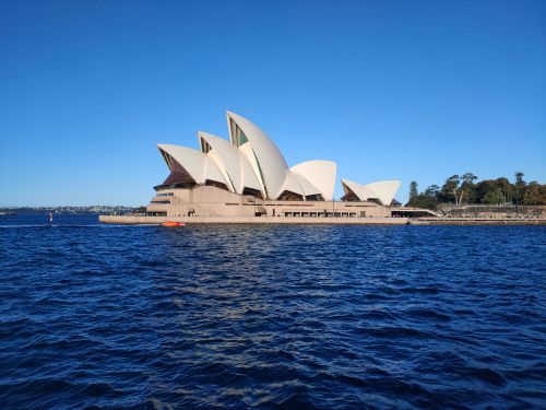 Free Stunning view of Sydney Opera House with vibrant blue sky and harbor waters. Stock Photo