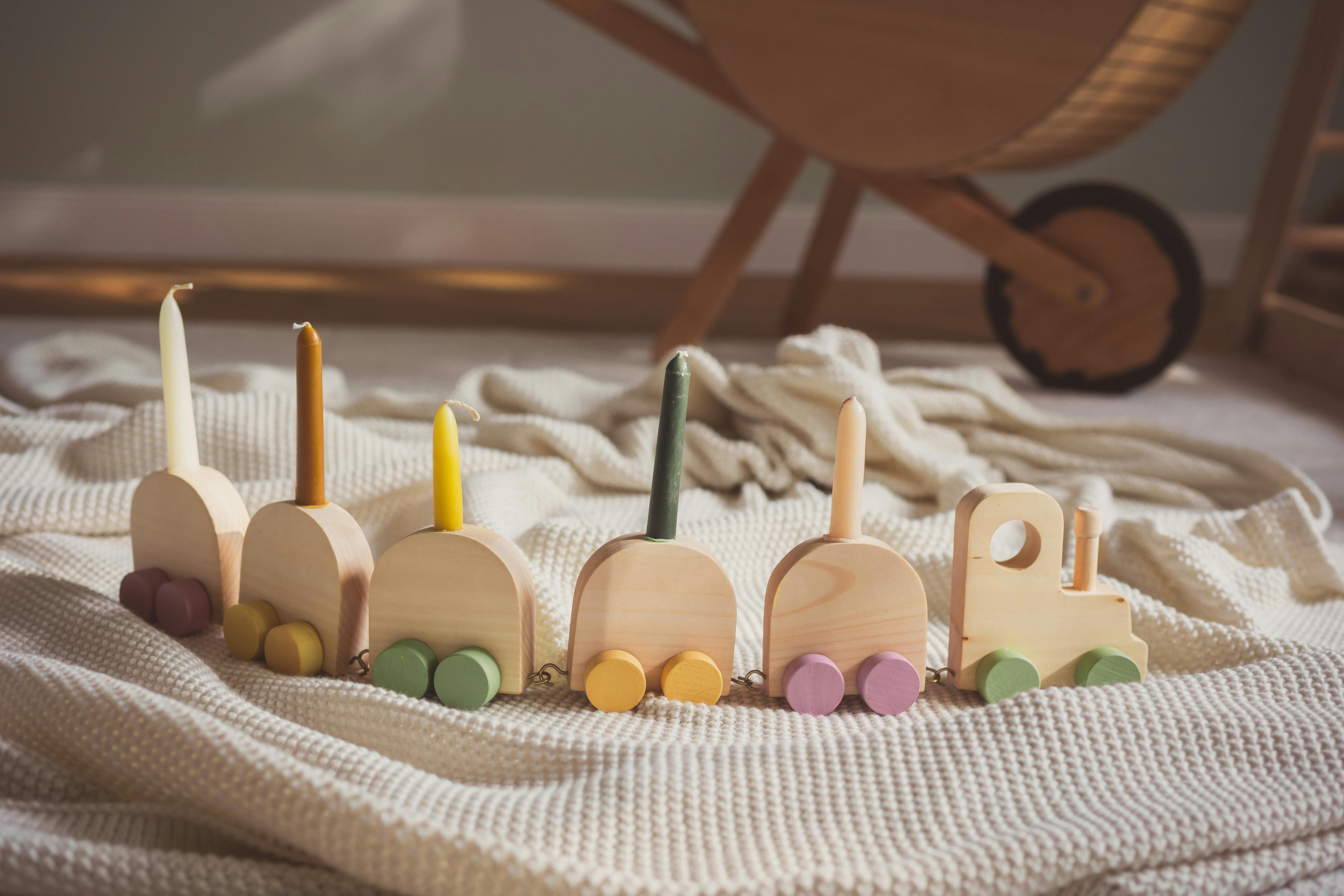 A wooden toy train with colorful wheels resting on a soft blanket in a cozy indoor setting.