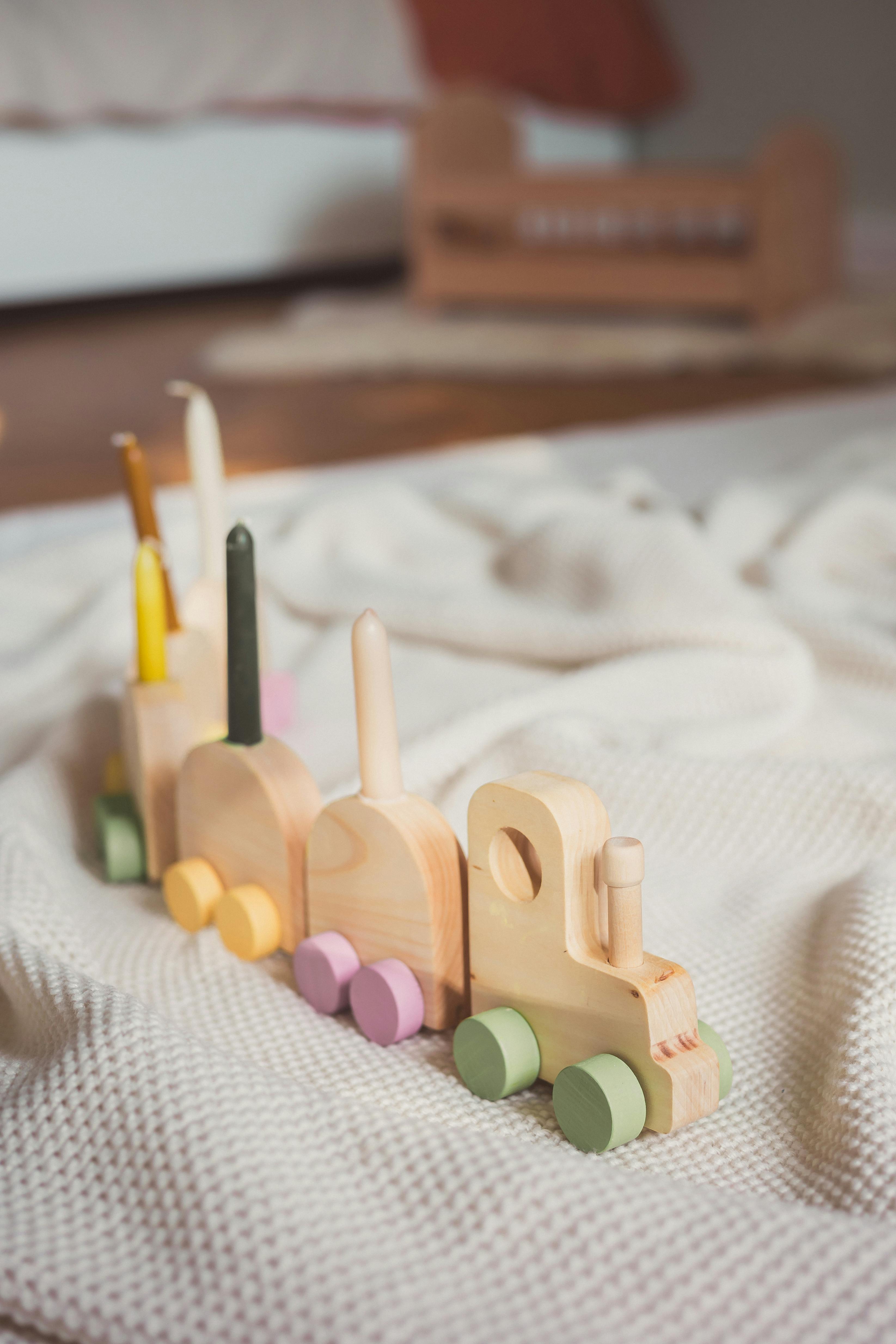 A close-up of a vibrant wooden toy train resting on a cozy knitted blanket, creating a warm, playful ambiance.