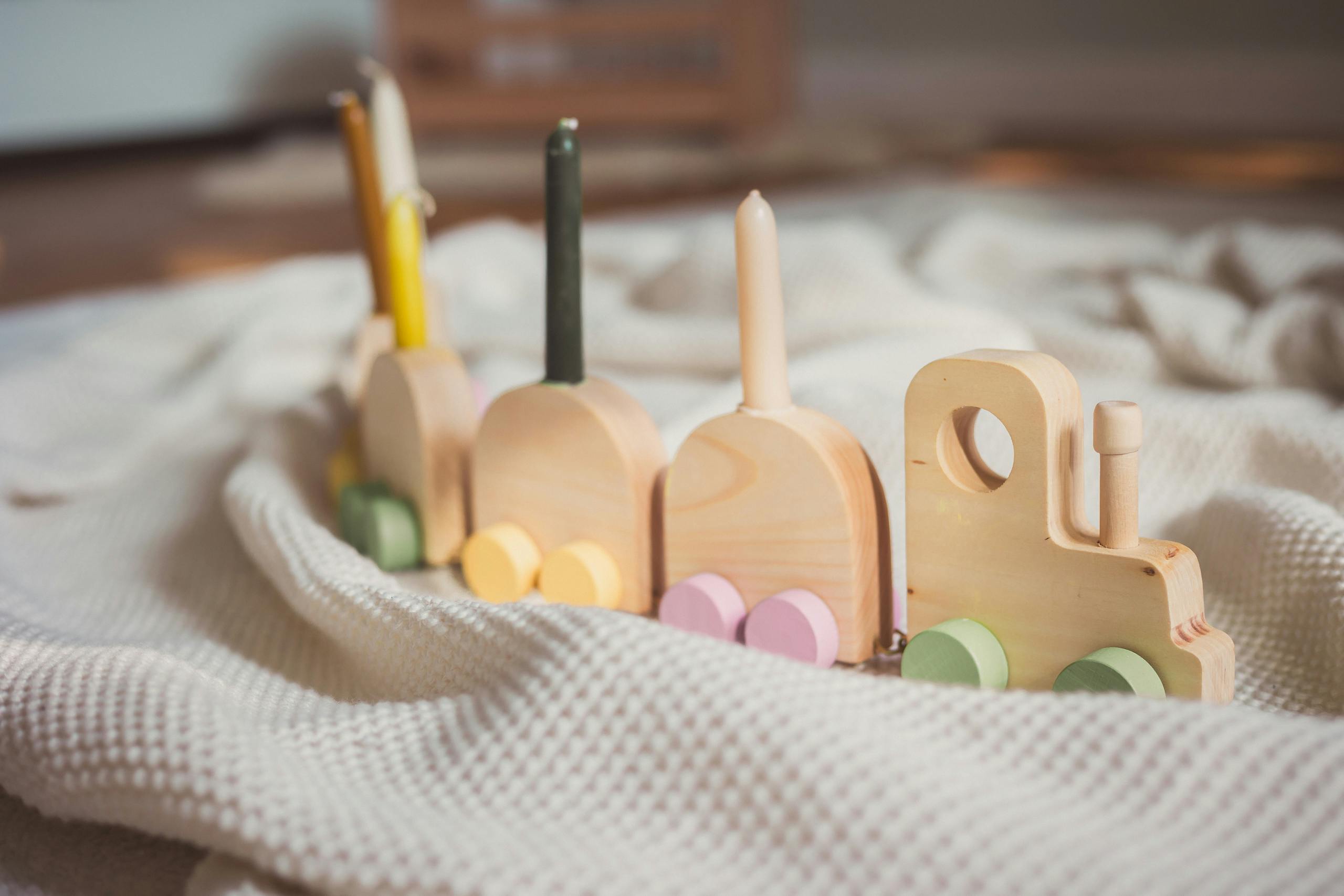 Charming wooden toy train set resting on a cozy knitted blanket in soft lighting.