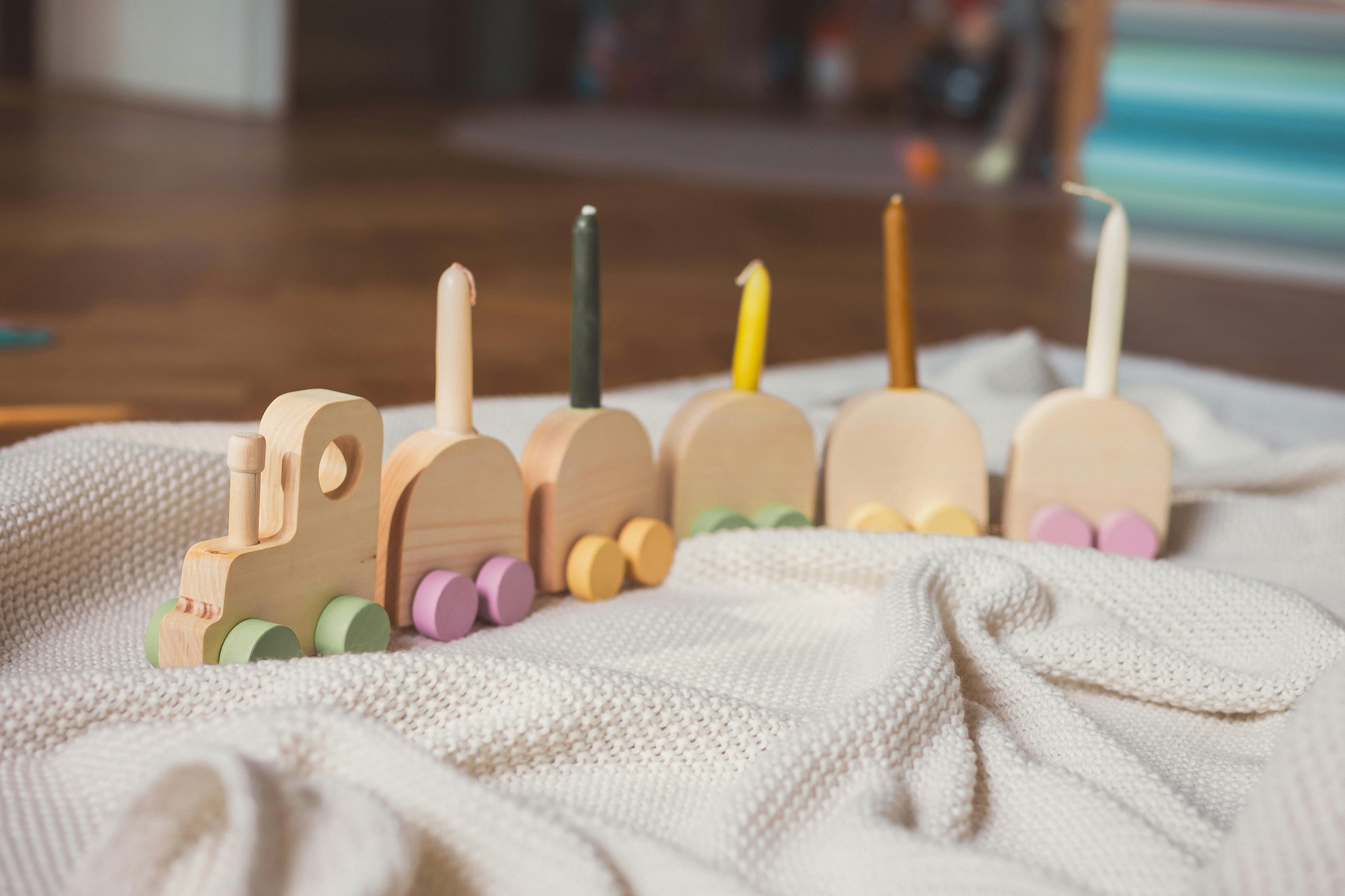 Charming wooden toy train with candles on a soft knit blanket indoors.