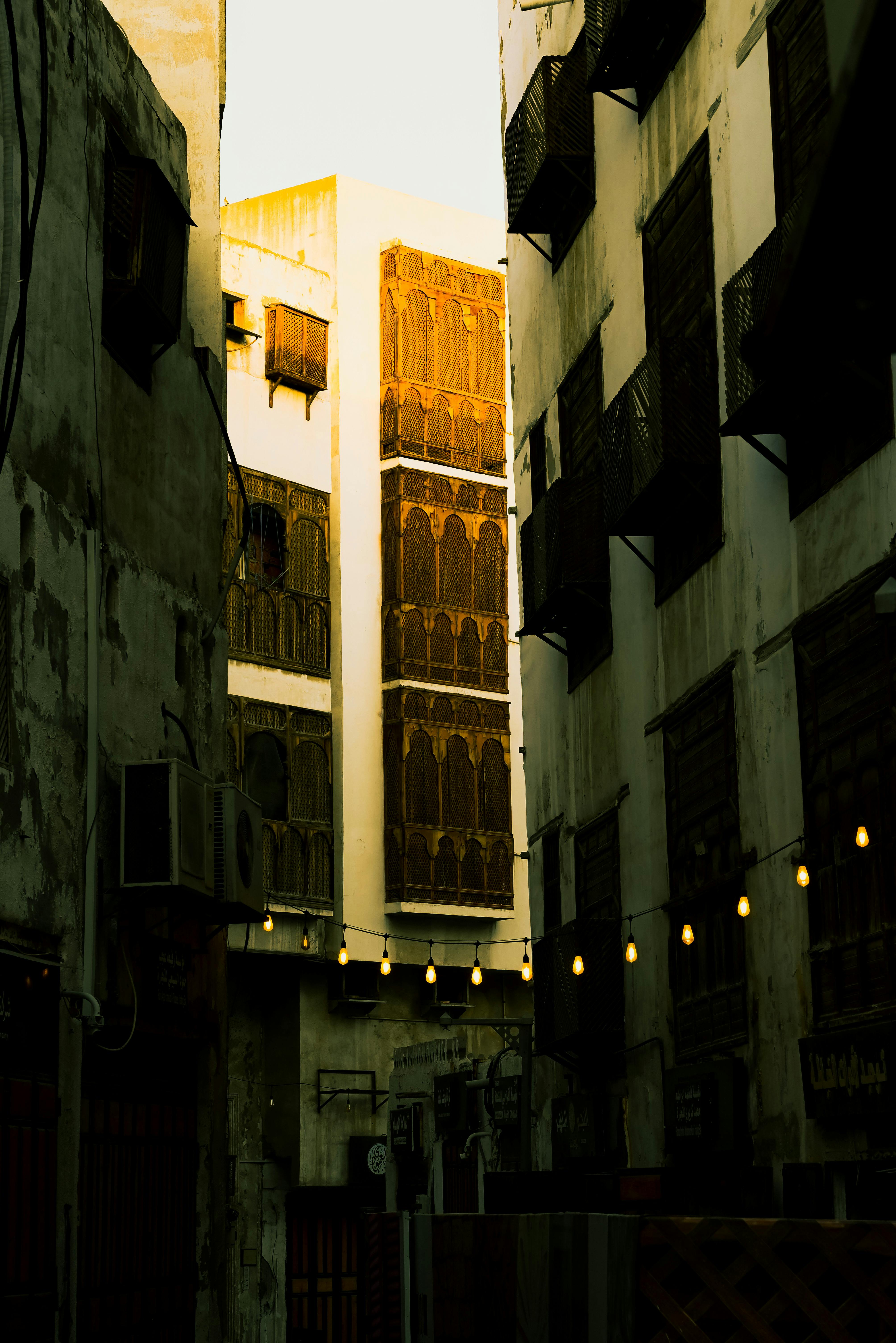 Ücretsiz Yumuşak ışık altında süslü ahşap pencerelerle geleneksel mimariyi sergileyen dar bir sokak. Stok Fotoğraflar