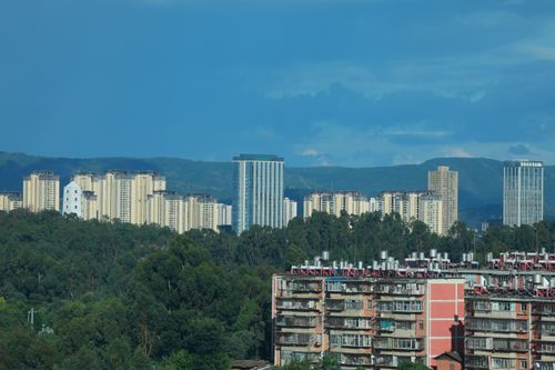 Free City skyline showcasing modern high-rise buildings with a backdrop of lush green hills. Stock Photo