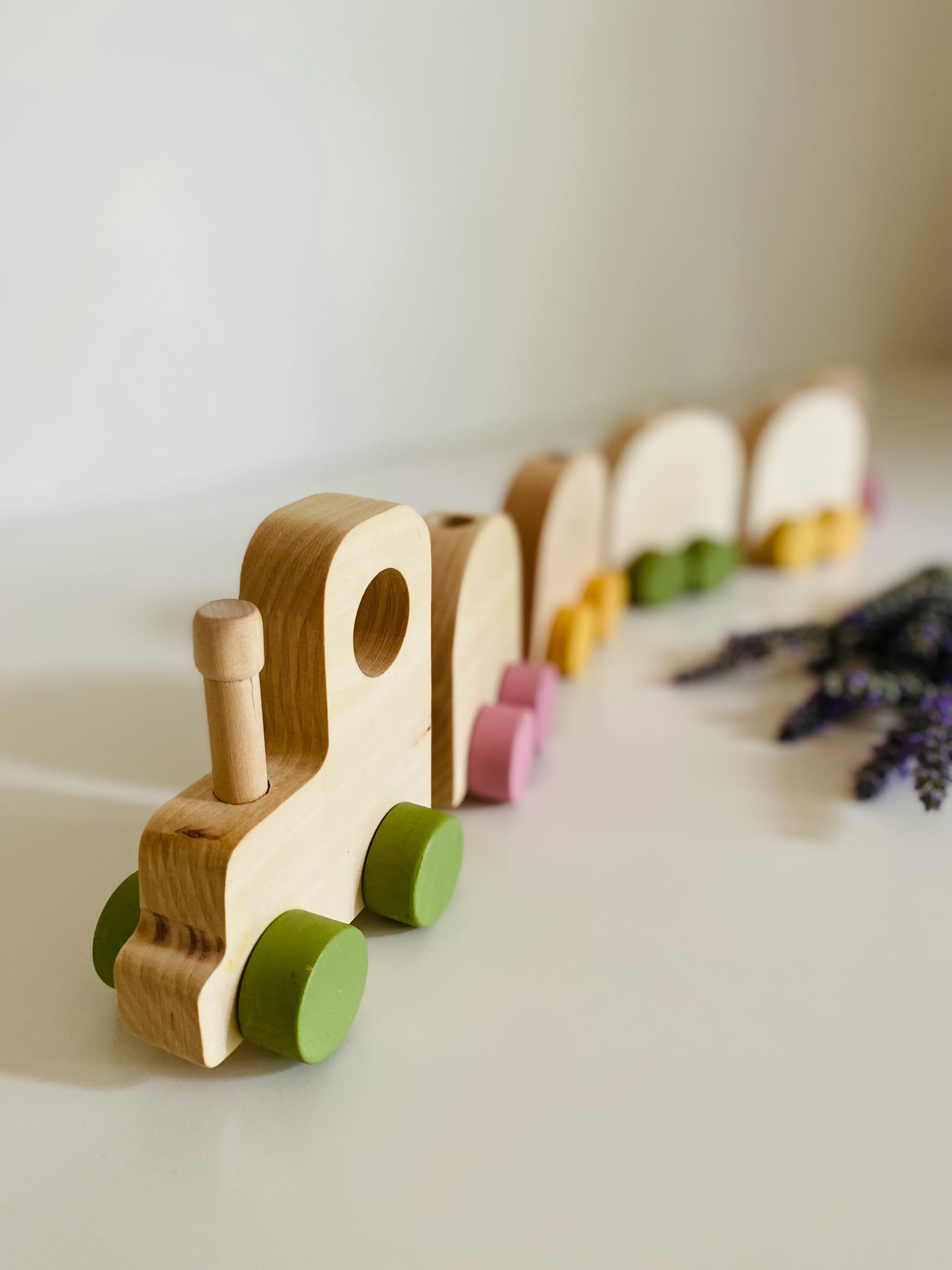 Wooden toy train with colorful wheels on a white surface, perfect for kids.
