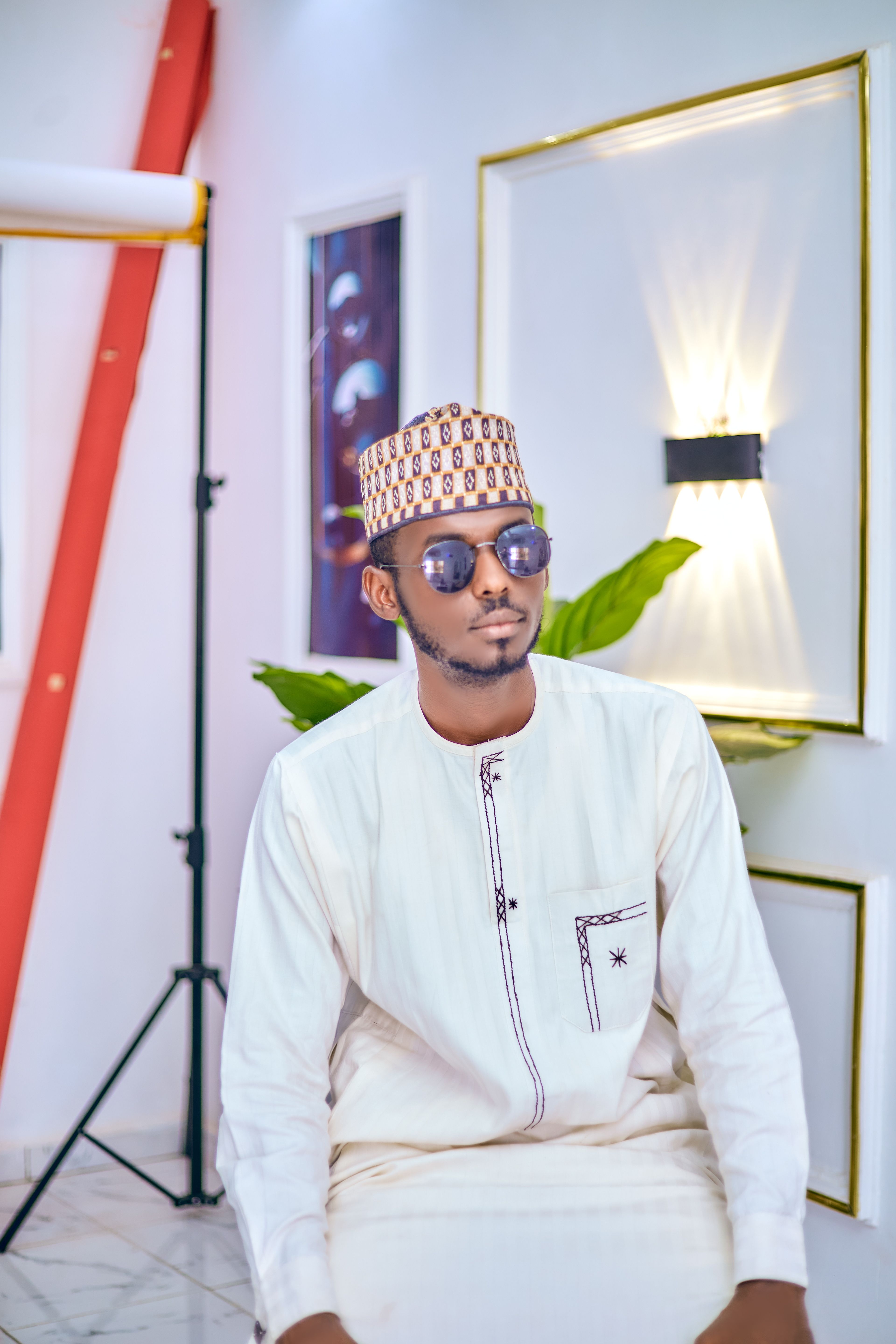 Man wearing traditional clothing and sunglasses in a modern indoor setting.