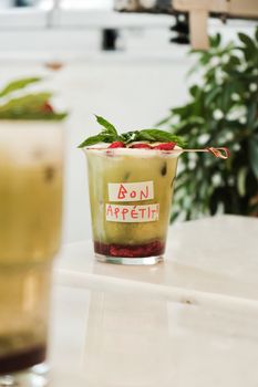 Delicious iced matcha latte topped with fresh berries and mint, perfect for a refreshing treat.