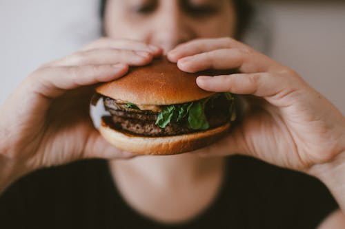 Free Person Holding a Burger Stock Photo