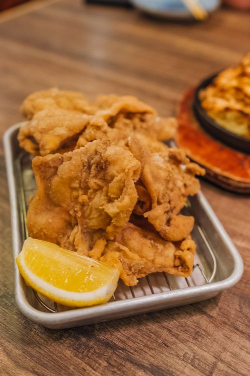 Free Delicious crispy fried chicken pieces served with a fresh lemon wedge on a metal tray. Stock Photo